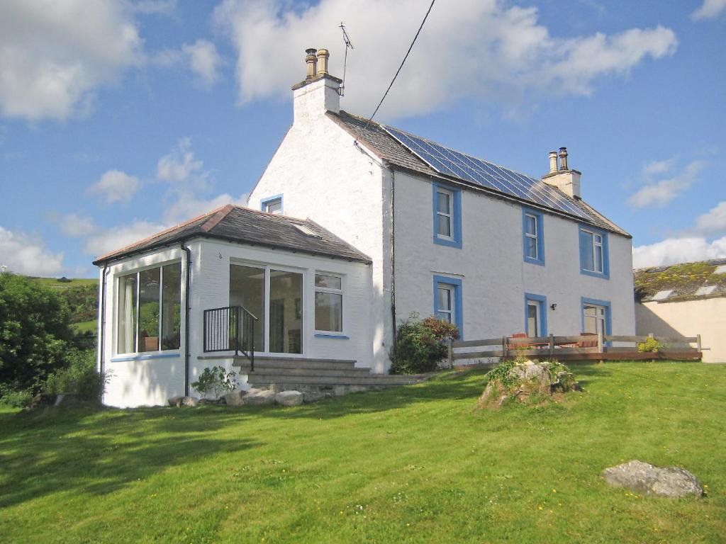 a white house on top of a grass field at Kirkbride Farmhouse - 28471 in Creetown