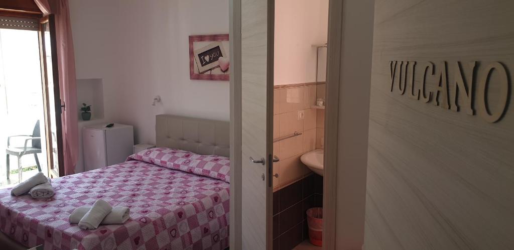 a small bedroom with a bed and a bathroom at Eolie House in Tropea