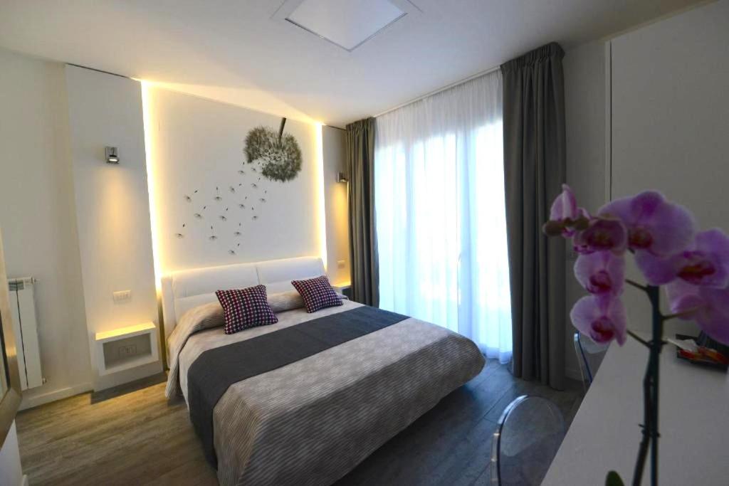 a bedroom with a bed and a vase of purple flowers at La Brise in Marina di Pietrasanta
