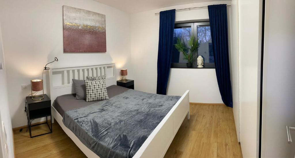 Schlafzimmer mit einem Bett und einem Fenster mit blauen Vorhängen in der Unterkunft Ferienwohnungen Nalbach Bierbach in Nalbach