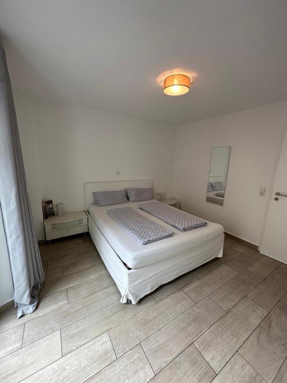 Schlafzimmer mit einem weißen Bett und Holzboden in der Unterkunft Apartments am Moselufer in Bruttig-Fankel