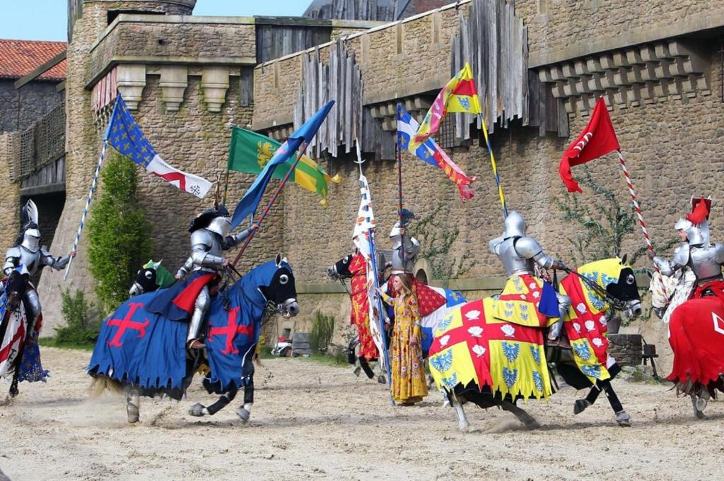 un gruppo di persone in armatura che cavalcano cavalli con bandiere di L'Udon-Thani gîte de groupe à 4 min du Puy du Fou a Les Épesses