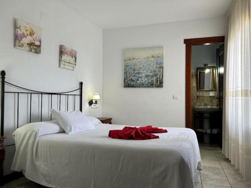 Un dormitorio con una cama blanca con una cinta roja. en Hotel Al-Andalus, en Torrox