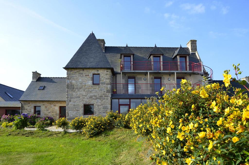 une grande maison sur une colline avec des fleurs jaunes dans l'établissement Domaine de Kerzuat, à Plouarzel