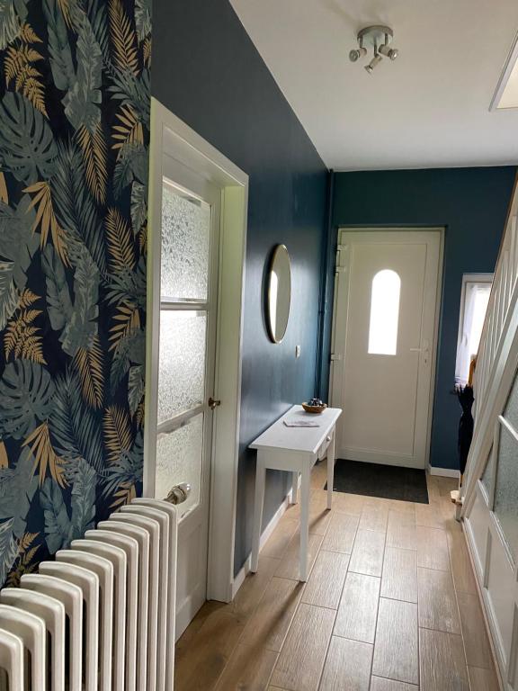 un pasillo con una mesa blanca y una pared azul en La maison du bienvenu en Namur
