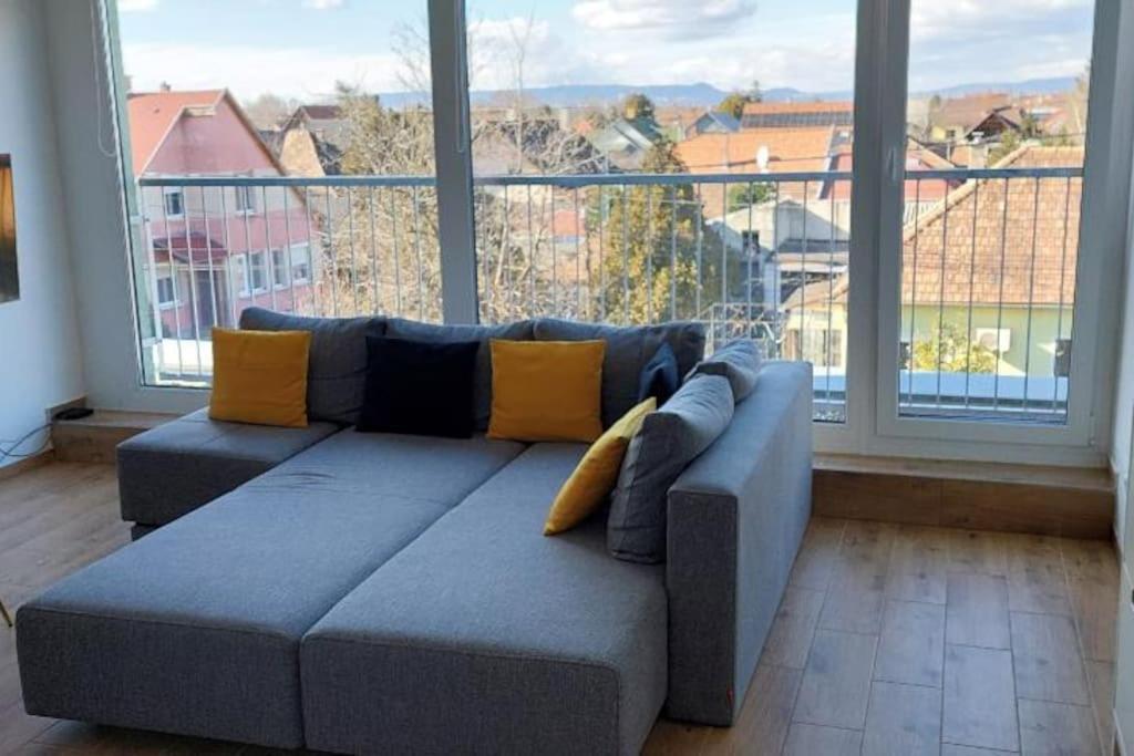 a couch in a living room with a large window at Fiume Panorama Residence with free garage in Budapest