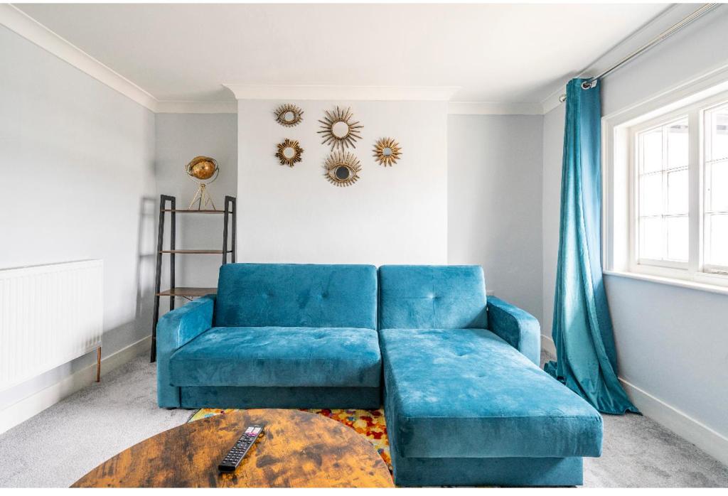 梅德斯通的住宿－Romney Home，客厅配有一张蓝色的沙发,配有一张桌子