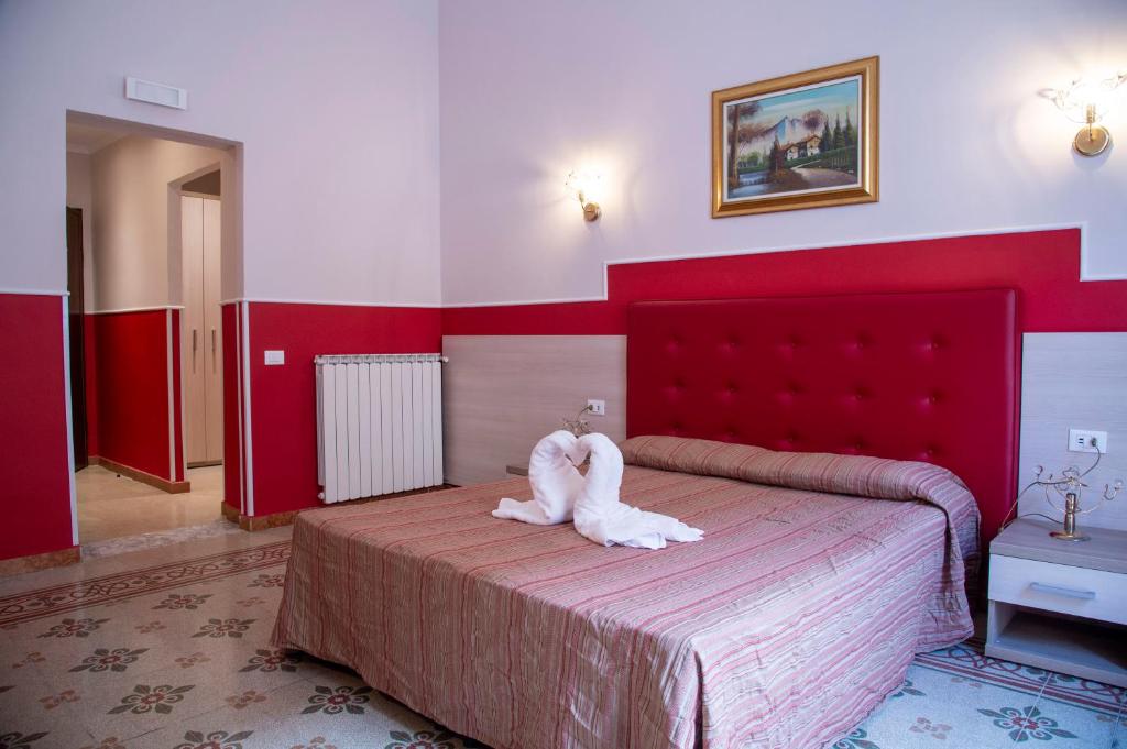 ローマにあるドムス ナポレオーネのベッドルーム1室(赤い大型ヘッドボード付きのベッド1台付)