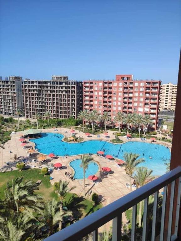 een balkon met uitzicht op een resort met 2 zwembaden bij العلمين in El Alamein