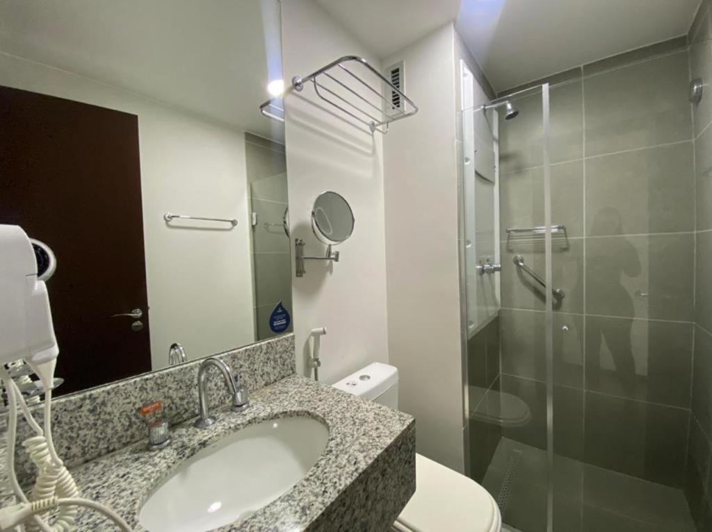 ein Bad mit einem Waschbecken und einer Glasdusche in der Unterkunft Flat Premiere Rio Centro in Rio de Janeiro