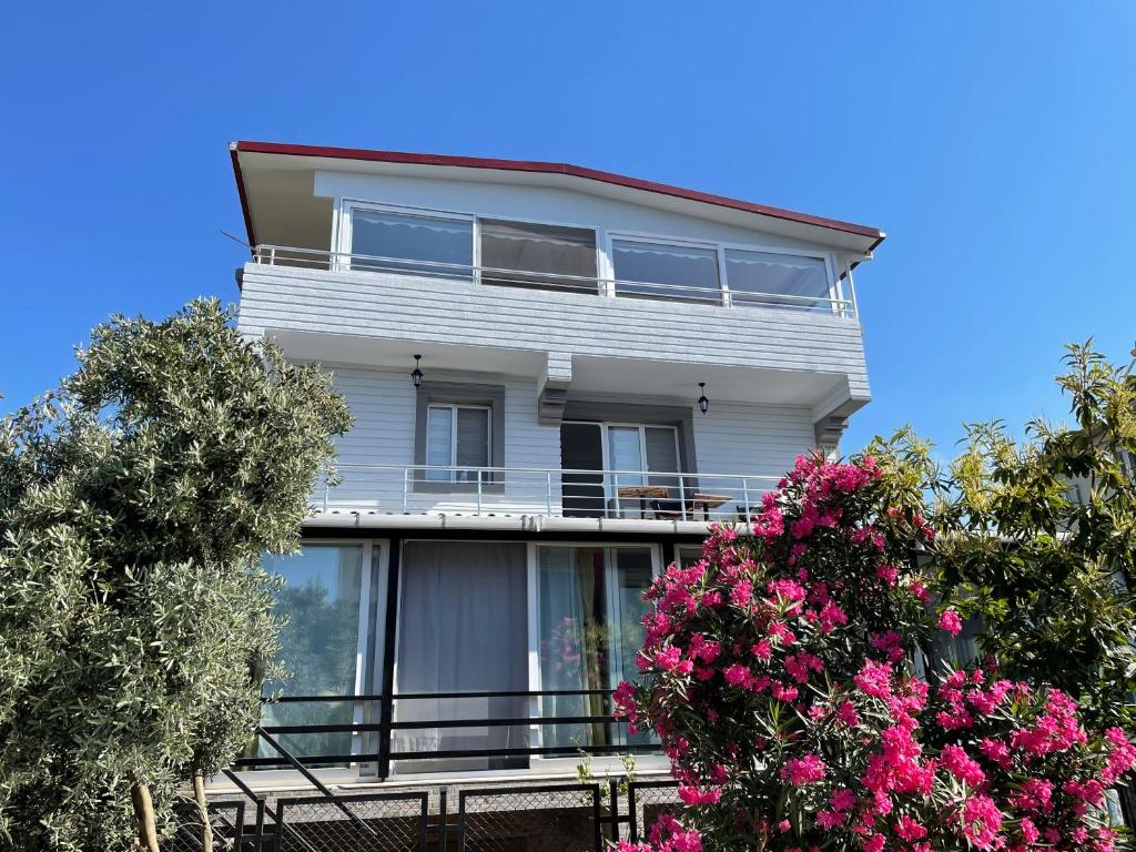 ein weißes Haus mit Fenstern und rosa Blumen in der Unterkunft Can’s Homes in Kusadası