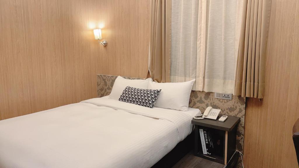 um quarto de hotel com uma cama e um telefone numa mesa em Welove meworld Inn em Taipei