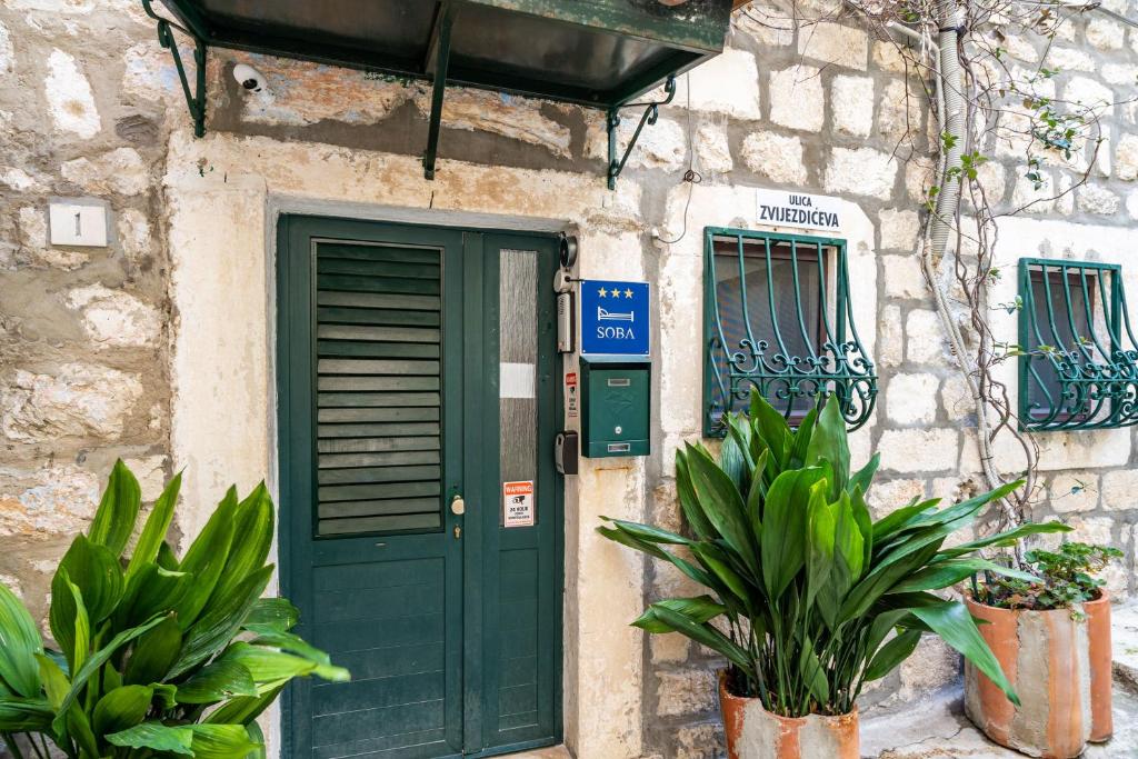 a green door on a stone building with plants at Tulip Old Town in Dubrovnik