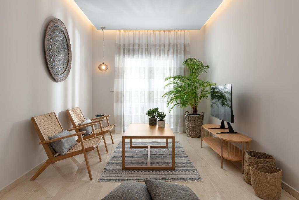 een woonkamer met een tafel en stoelen en een televisie bij Stylish Rhodes Apartment with Prime Location - L & C City Escape in Rhodos-stad