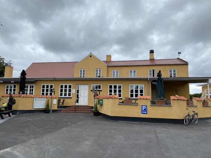 un grand bâtiment jaune avec un vélo garé devant lui dans l'établissement Orø Kro & Hotel, à Orø
