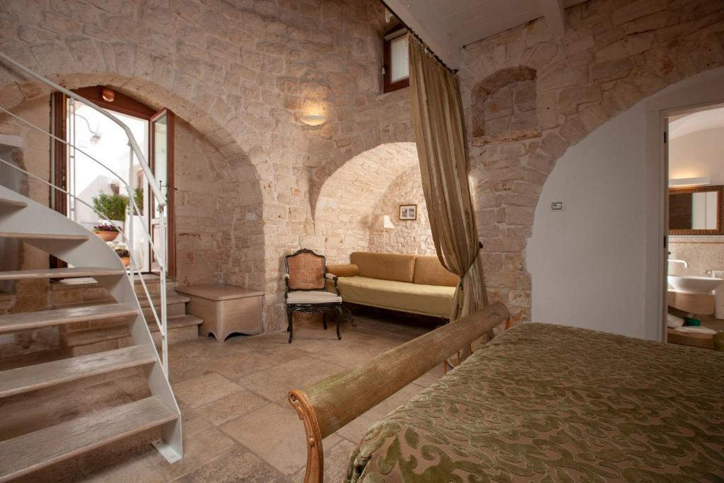 una camera da letto con un muro in pietra, un letto e un divano di Le Alcove - Luxury Hotel nei Trulli ad Alberobello