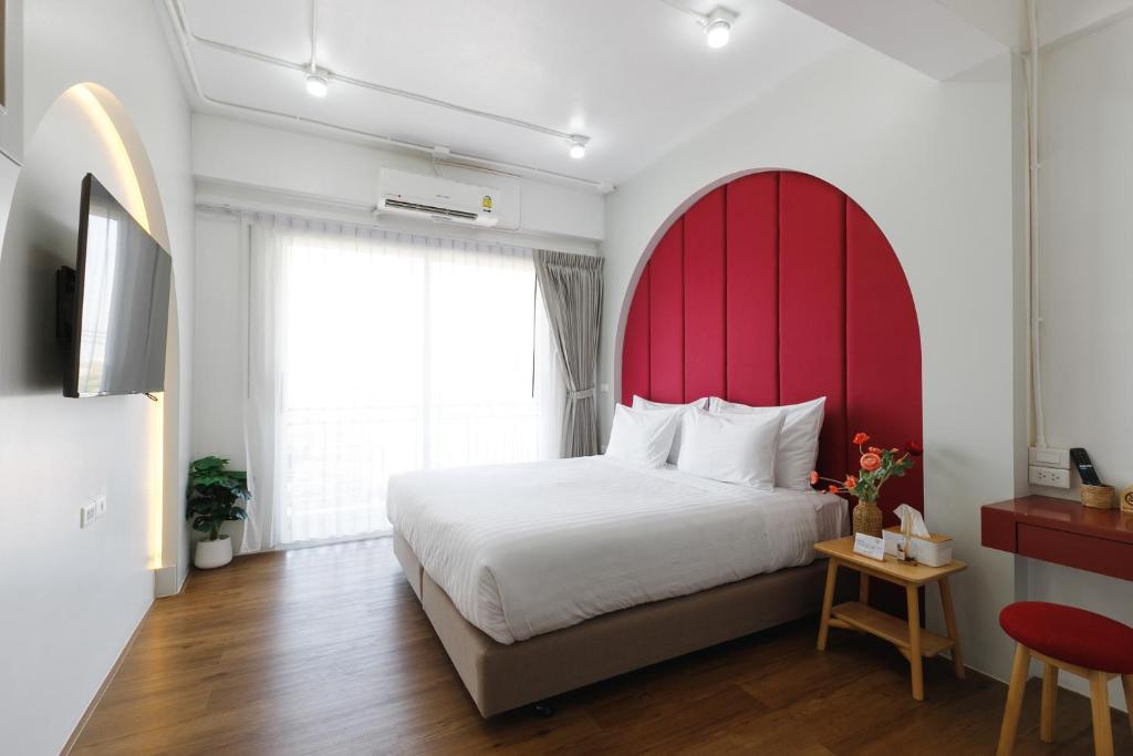 a bedroom with a large bed with a red headboard at Grow home -Stay and space, Self check-in in Chiang Rai