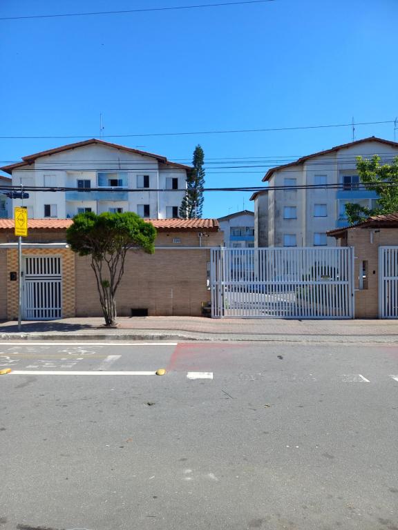 an empty street with a white fence and buildings at Apto da Andreia in Praia Grande