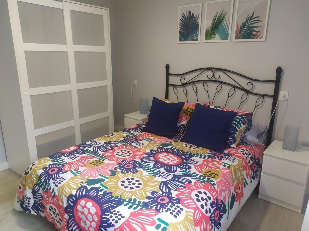 a bed with a colorful comforter and two pillows at Alquiler integro casa próxima a Colunga in Colunga