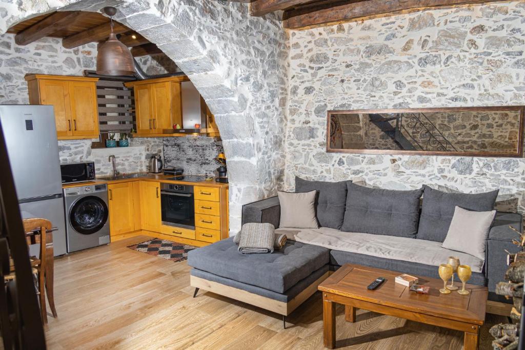a living room with a gray couch and a kitchen at Stefanis Guest House in Krásion
