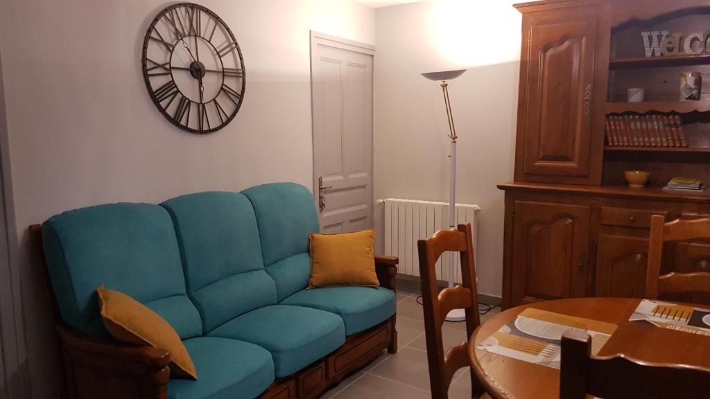 a blue couch in a living room with a clock on the wall at Maison de Romagers in Aumont-Aubrac