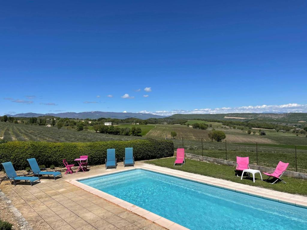 a swimming pool with pink and blue chairs next to it at La Ferme l'Etang in Vachères