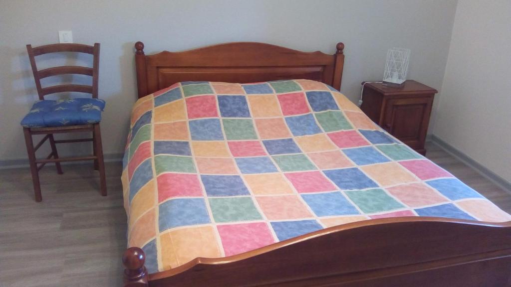 a bed with a colorful quilt on it with two chairs at Maison de Romagers in Aumont-Aubrac