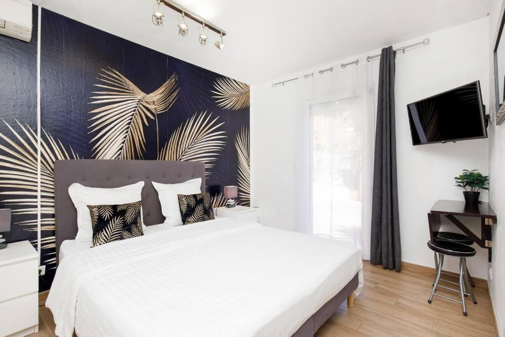 ein Schlafzimmer mit einem weißen Bett und einer Wand mit einem Wandbild in der Unterkunft Studio au calme, avec terrasse et parking à Eze village in Èze