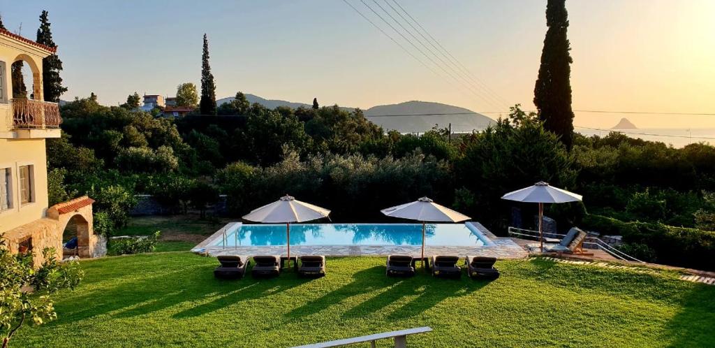 two umbrellas and a swimming pool in a yard at Private Swimmingpool in Cottage in Poros
