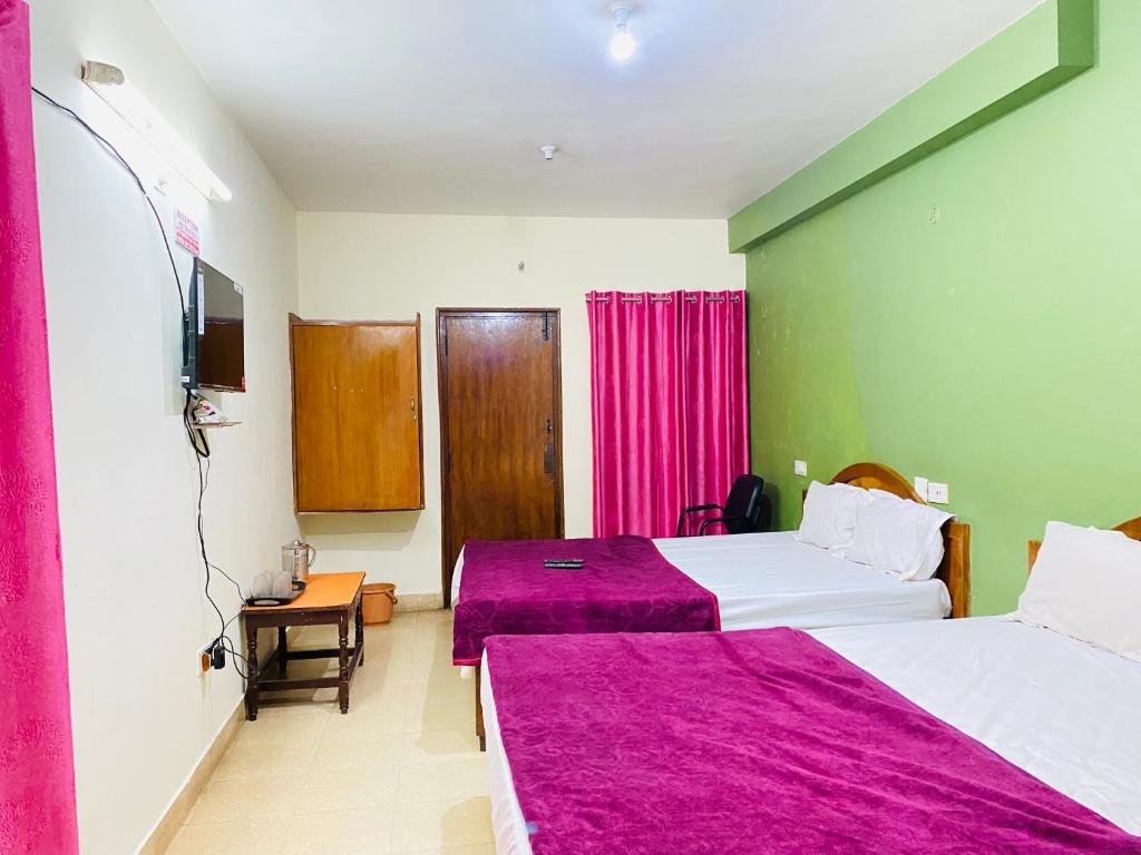 a hotel room with two beds and a tv at Hotel Nakshatra in Ooty