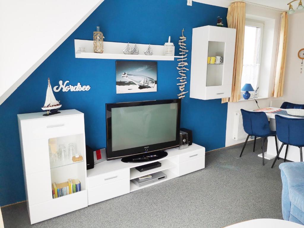 ein Wohnzimmer mit einem TV und einer blauen Wand in der Unterkunft Skipper in Dorum Neufeld
