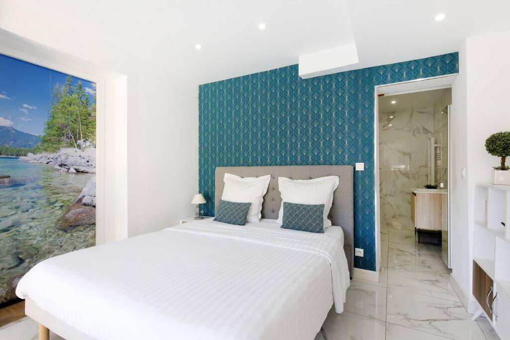 1 dormitorio con cama blanca y pared azul en Studio tout confort avec parking et terrasse à Eze village, en Èze