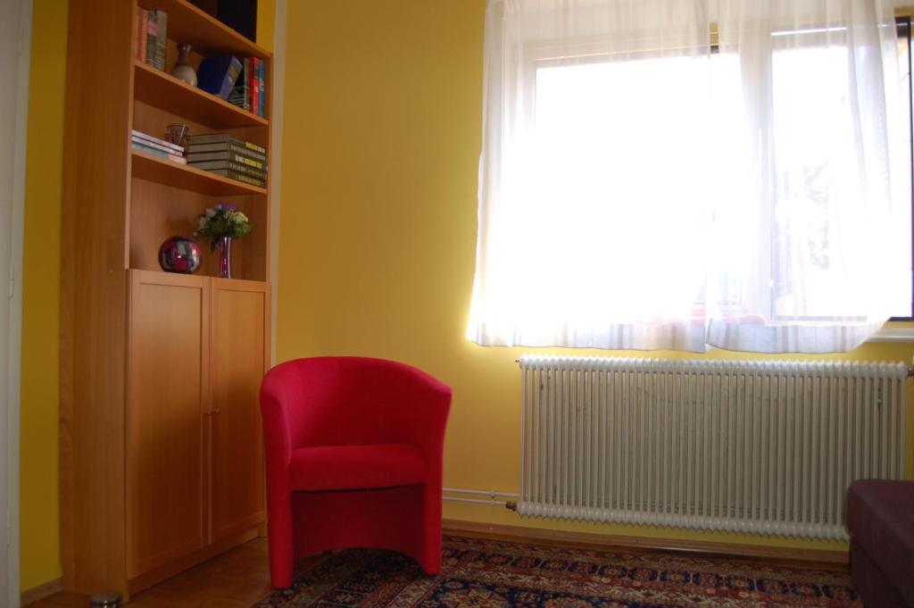 a red chair in a room with a window at Garden Apartment Donau-City (P&R) in Vienna