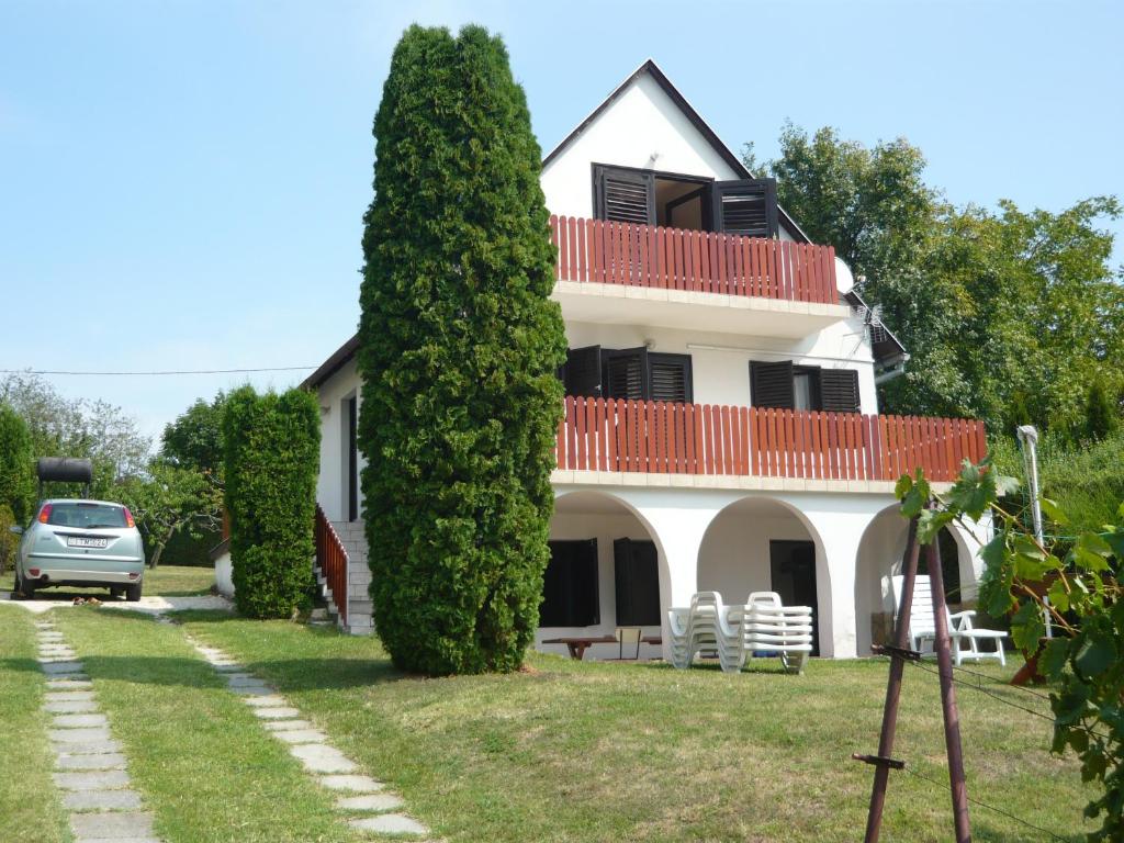 una casa con un gran arbusto delante de ella en Judit Vendégház a Balatonnál, en Vonyarcvashegy