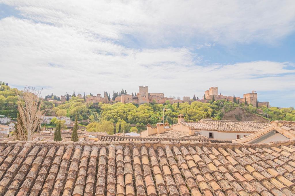 an old roof of a building with a castle in the background at Casa de la Acequia by Florentia Homes in Granada
