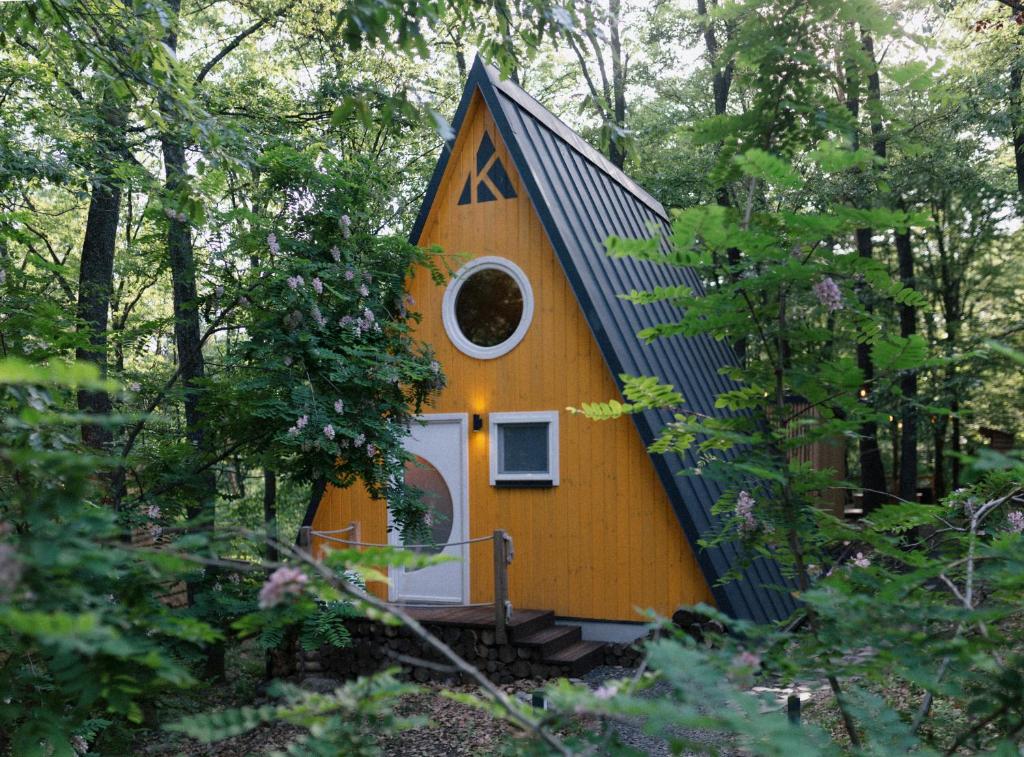 una casa amarilla con techo negro en el bosque en Kabinka Mátra, en Pásztó