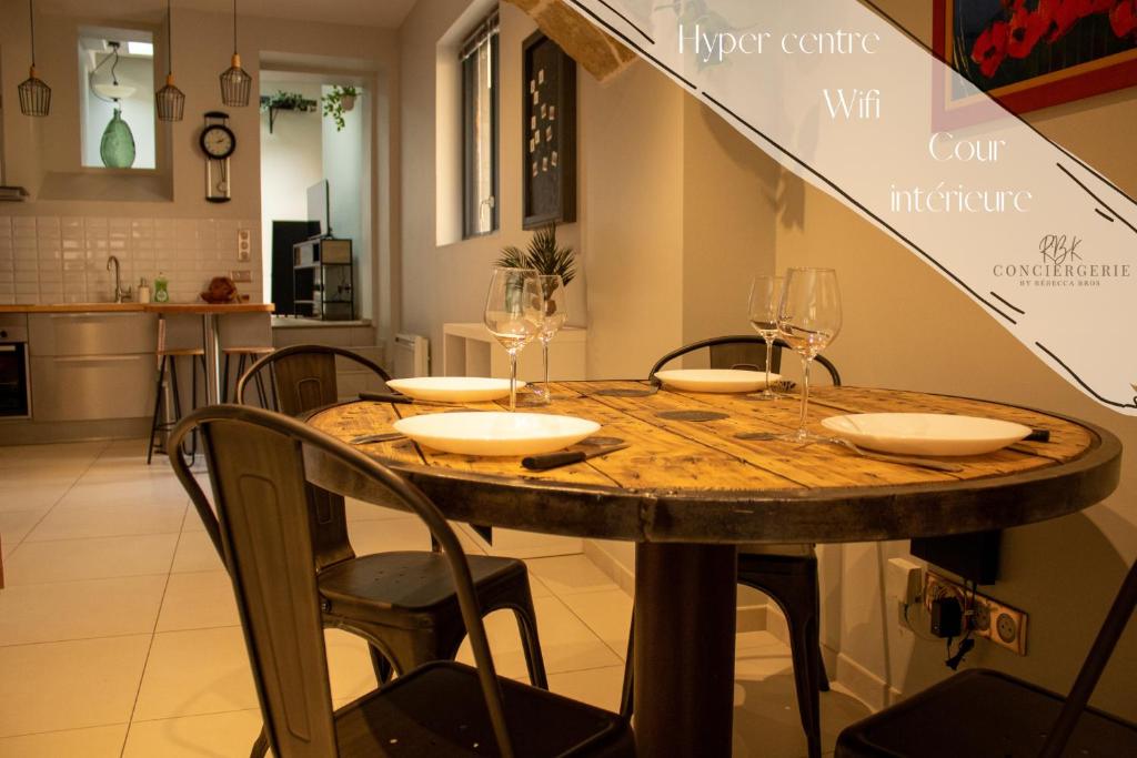 uma mesa de jantar com cadeiras e copos de vinho em Le Triplex - 4 pers - Wifi - Centre ville em Mende