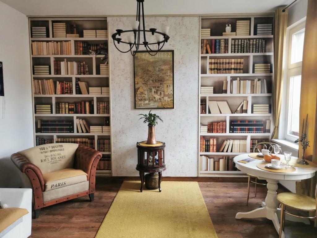 a living room with book shelves and a chair and a table at Mieszkanie Przy Plaży in Sopot