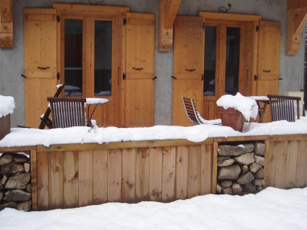 un porche cubierto de nieve con 2 sillas en la nieve en Chalet Rum Doodle, en Pralognan-la-Vanoise