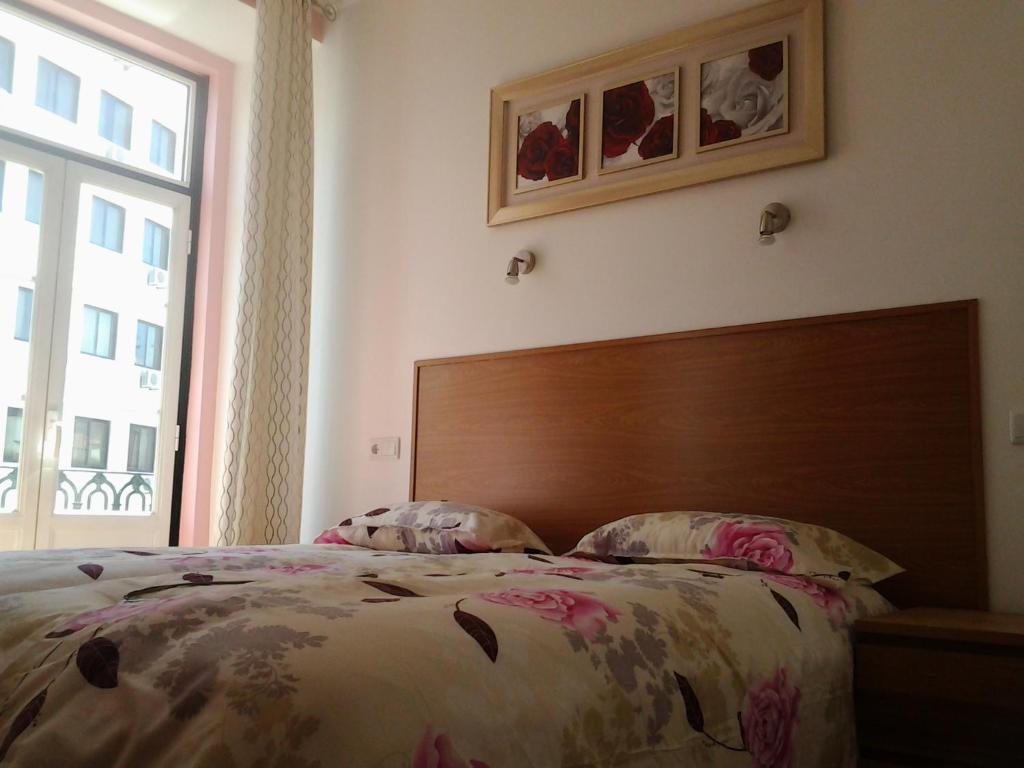 um quarto com uma cama com uma cabeceira em madeira e uma janela em Baixasuites em Lisboa