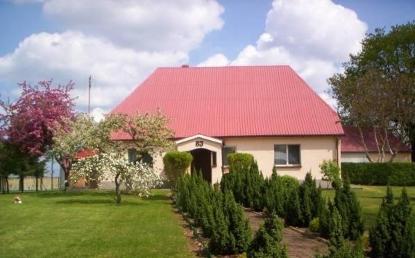 uma casa com um telhado vermelho e um quintal com árvores em Agroturystyka Pod Brzozami em Karsibór