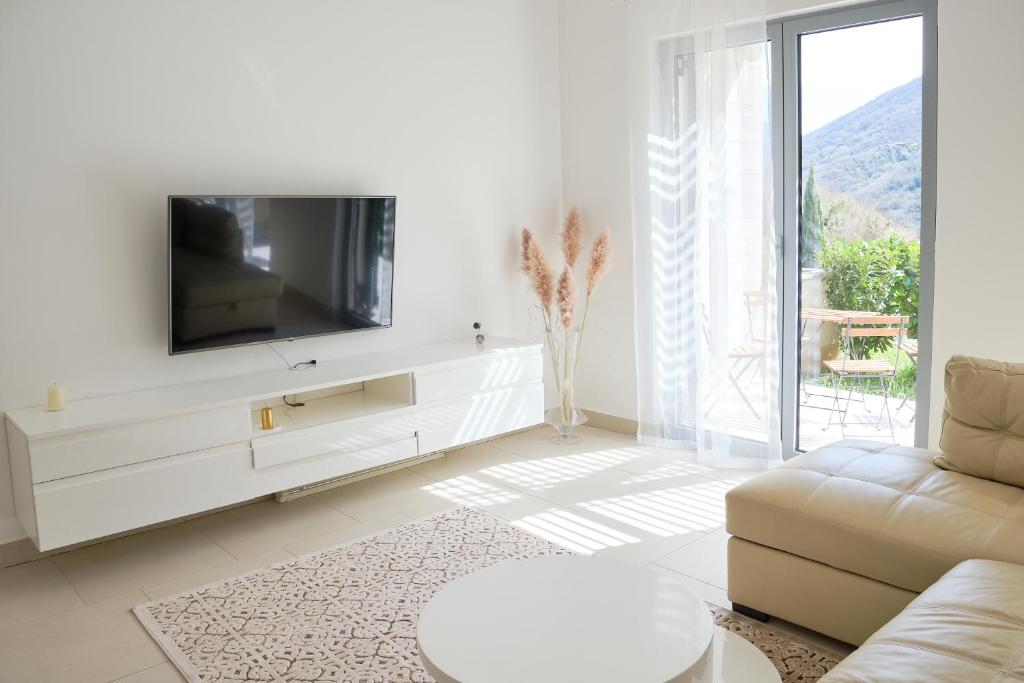 sala de estar blanca con TV y sofá en Lavandar Bay C03, en Kotor