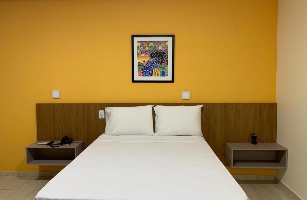 een slaapkamer met een wit bed en een gele muur bij Boulevard Park Hotel in São Luís