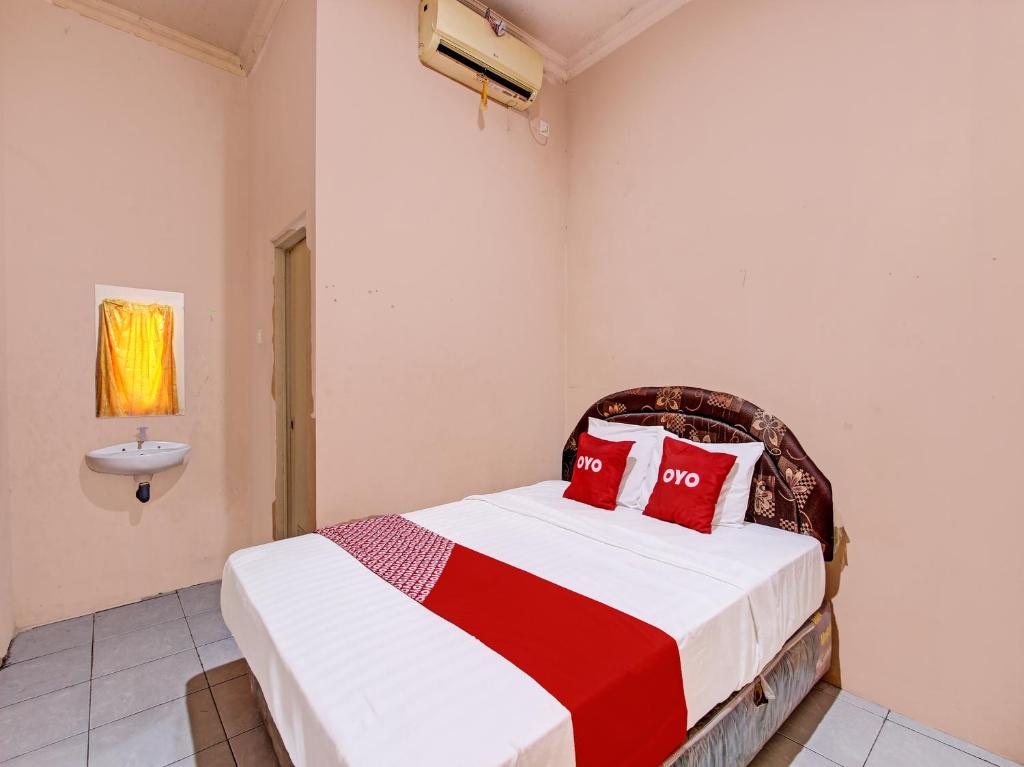 a bedroom with a bed with red pillows and a sink at OYO 92459 Cahyo Kost 2 in Semarang