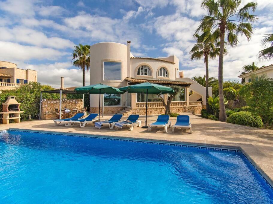 een huis met een zwembad met stoelen en parasols bij Casa Calma in Cala Santanyi