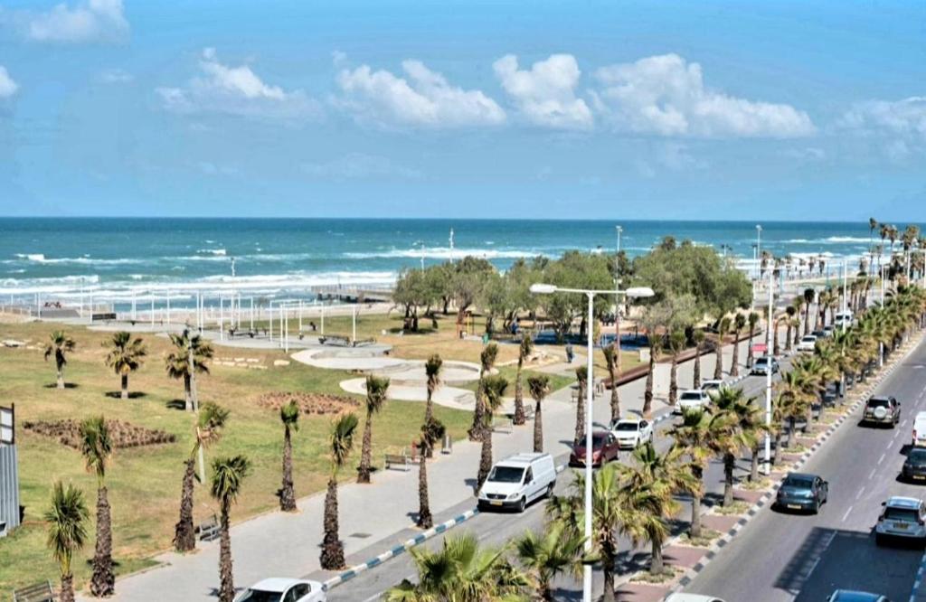 een straat met auto's geparkeerd op een weg met palmbomen bij Hotel Apartment Short Term Tel Aviv Bat Yam 353 in Bat Yam