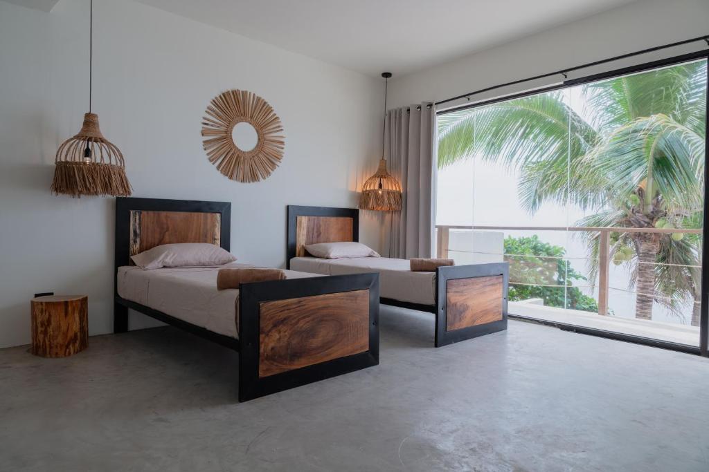 a bedroom with two beds and a large window at LAOLA SURF CAMP EL SUNZAL in La Libertad