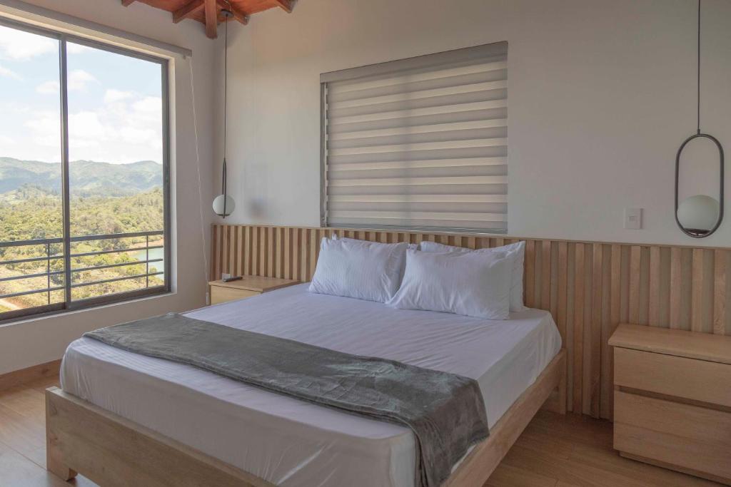 a bedroom with a bed and a large window at FINCA MONARCA in Guatapé