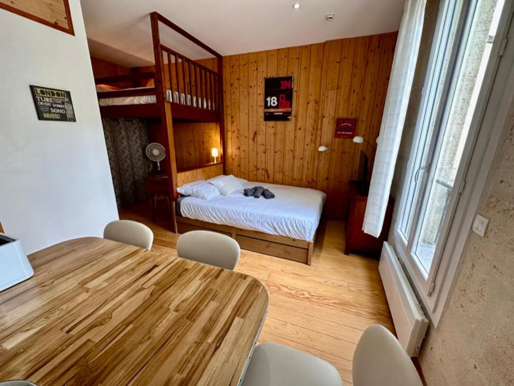a dining room with a table and a bed in a room at Le Woody, Centre-ville, Parking gratuit in Bordeaux