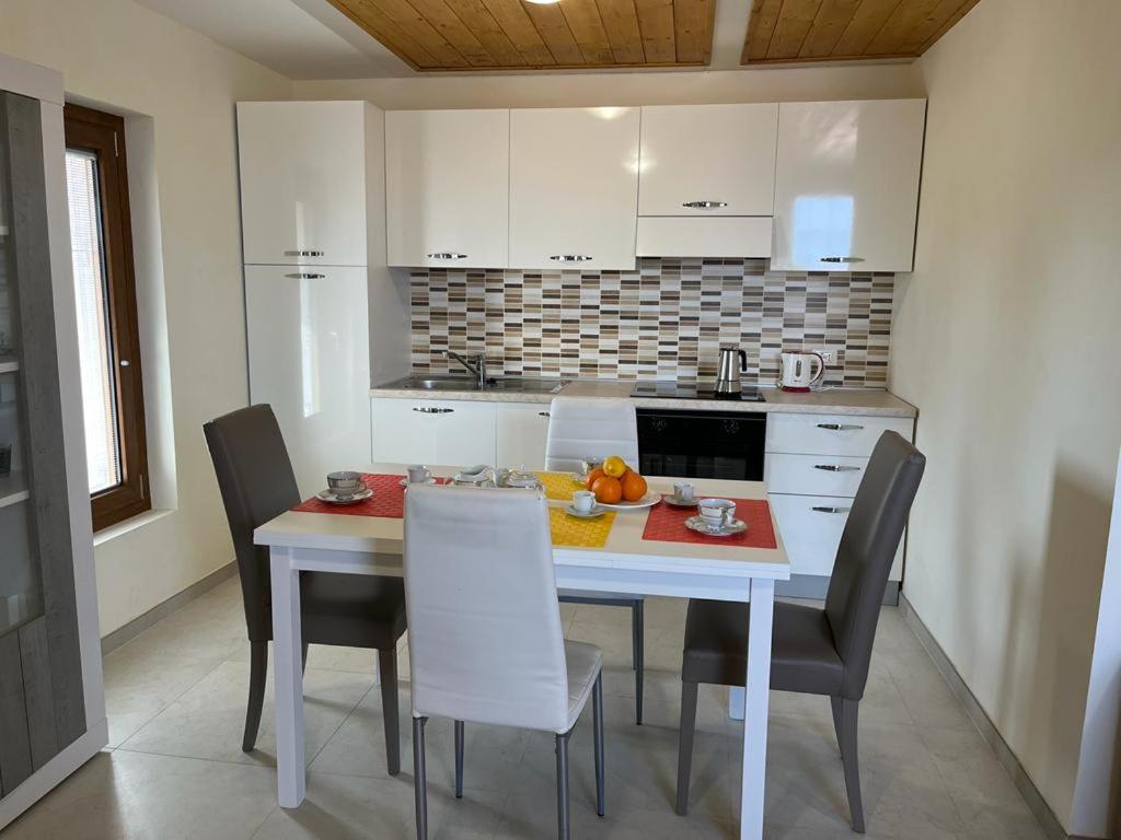 a kitchen with a white table and chairs and a kitchen with white cabinets at Perla Top Floor Apartment in Sirmione